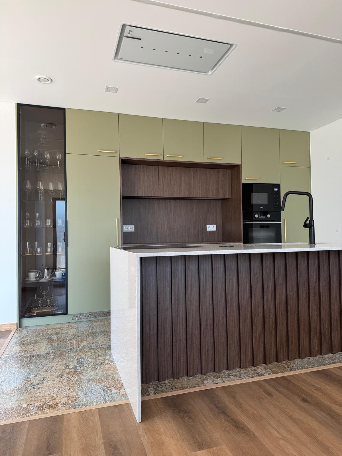 Cozinha em tom azeitona com vitrine e ilha revestida a madeira