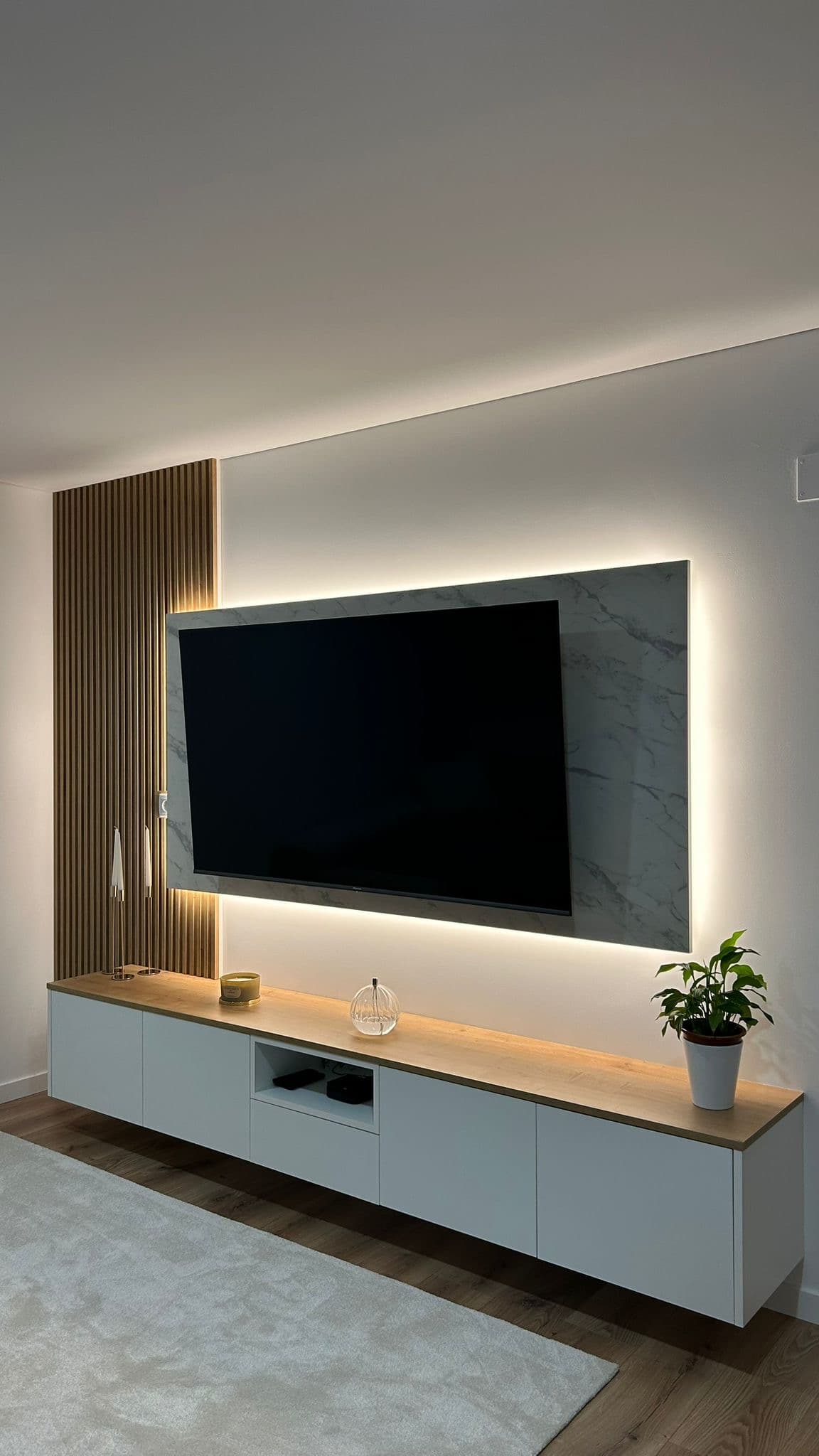 Móvel de televisão com painel em pedra retroiluminado e ripado de madeira