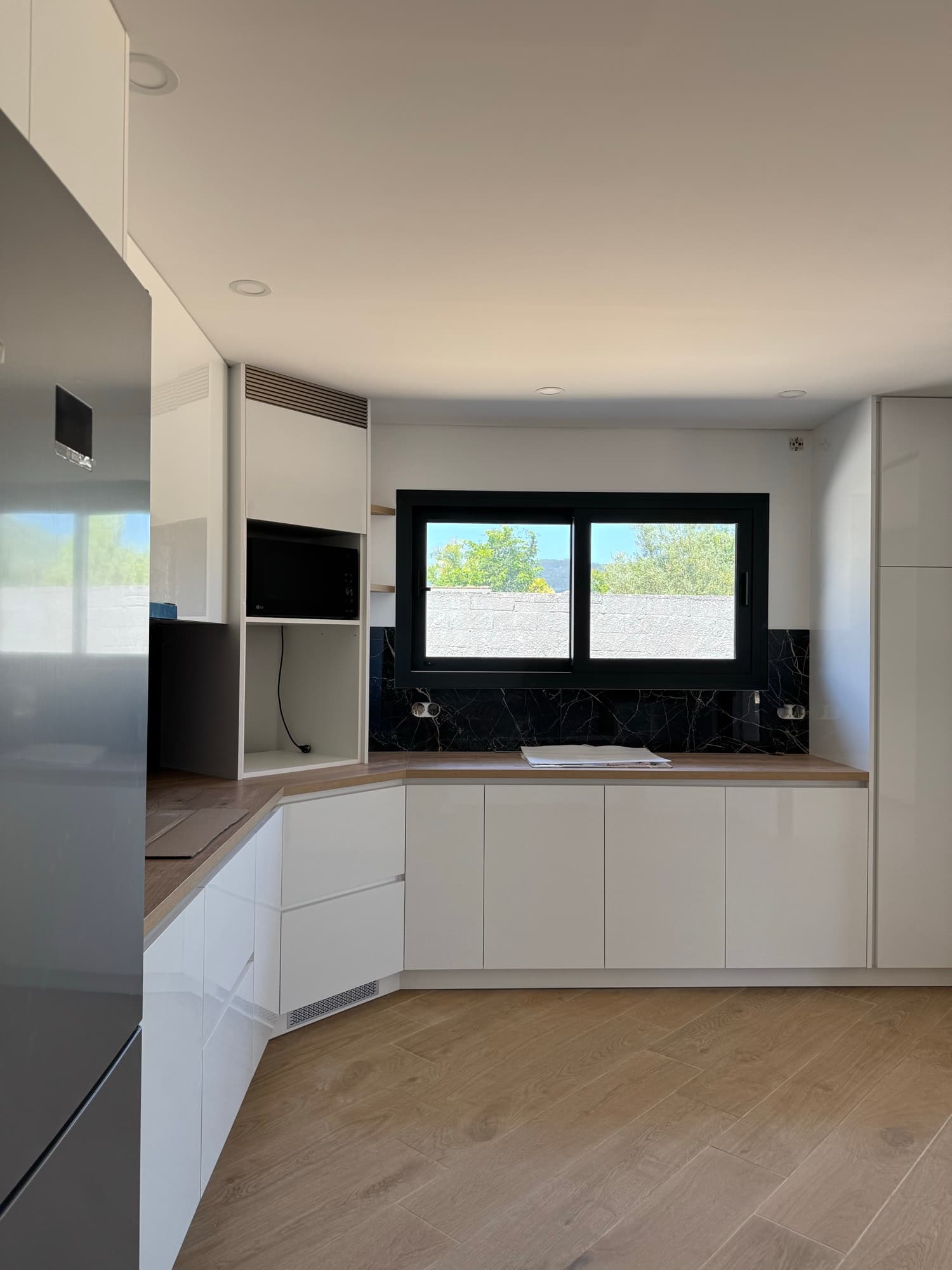 Cozinha lacada de branco com bancada em madeira e janela