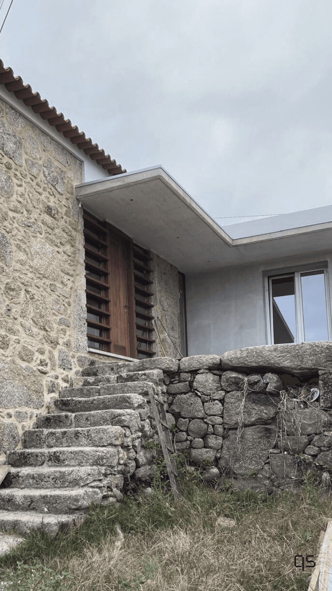 Casa em pedra com portadas e lâminas de madeira